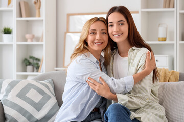 Obraz premium Young woman hugging her mother while sitting on sofa at home. International Hug Day