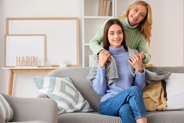 Middle-aged woman covering with blanket her adult daughter at home