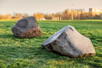 
A large stone lies on the grass in the park, landscaping, a big problem to solve