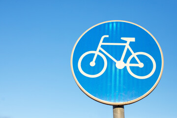 A bicycle path sign against the blue sky
