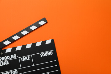 Clapperboard for filming on orange background, space for text