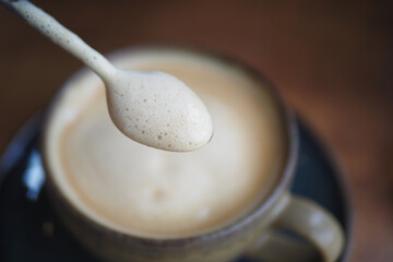 A closeup view showcasing a creamy coffee with beautiful swirls and a spoon resting in a white cup