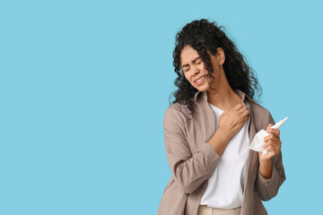 Young African-American woman suffering from skin allergy on blue background