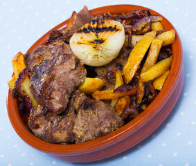 Image of braised tasty beef with potatoes and onions at clay pot on table