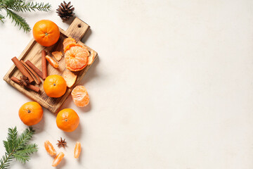 Wooden board of sweet tangerines with cinnamon, star anise and fir branches on white grunge...