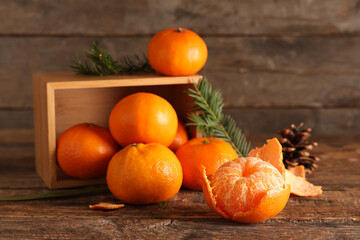 Box with sweet tangerines, cone and fir branches on wooden background