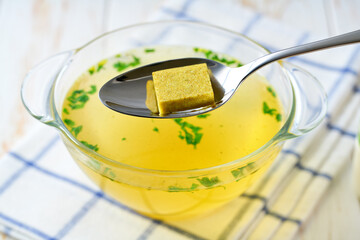 Broth cubes with ready to eat bouillon in a bowl on a kitchen table.
