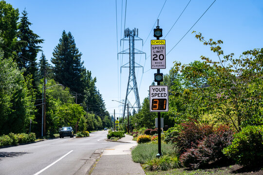 Traffic safety in a residential and school zone, electronic sign that displays your speed, speeding cars on road in 20 MPH school zone
