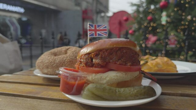 A cozy scene featuring an English bagel with a small British flag on a bagel, framed by a festive Christmas tree and a bustling street view in the background.