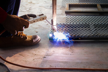 Welder is welding add joint at a construction site weld metal structures of  Steel frames and grids for use in construction.