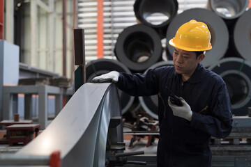 Asian male engineer inspecting quality rolls of galvanized or metal sheet. Male engineer working in...