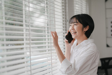 Fototapeta premium Cheerful woman on phone cozy home lifestyle image bright interior natural light happiness concept