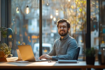 Smiling young man in headset using laptop at desk in modern office environment