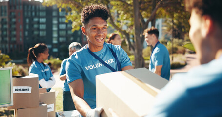 Box, volunteer team and man outdoor for donation, help and community care. NGO group, smile and...