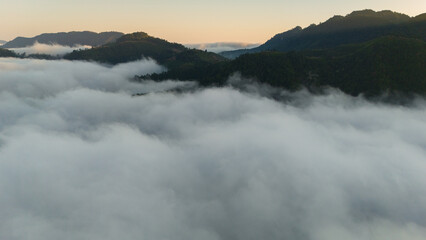 Fototapeta premium aerial overview of a sea of clouds glowing in golden hues during sunrise over hills
