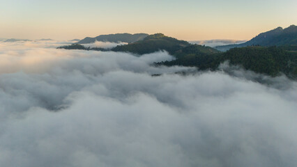 Obraz premium aerial overview of a sea of clouds glowing in golden hues during sunrise over hills