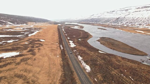 Car driving over a sand road next to a river in Iceland during the winter.
