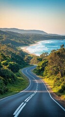Scenic coastal road winding through lush greenery with the ocean in the background
