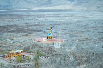 Obraz premium The Maitreya Buddha statue with Nubra Valley in the background from Diskit Monastery or Diskit Gompa, Nubra valley, Leh Ladakh