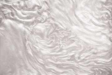 Obraz premium Shimmering silver abstract background. Liquid glitter paint texture waves and swirls. Beautiful shiny white glitter texture. Metallic silver paint close-up as a holiday background.