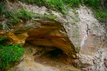 Fototapeta premium Sandstone cliffs and mystical caves along the Ahja River on the Taevaskoda hiking trail in summer near Põlva, Saesaare-Taevaskoja, Estonia 