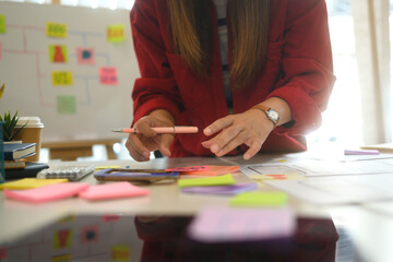 Fototapeta premium Young female designer reviewing wireframes and sketches on a desk