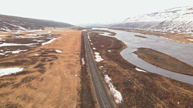 Car driving over a sand road next to a river in Iceland during the winter.