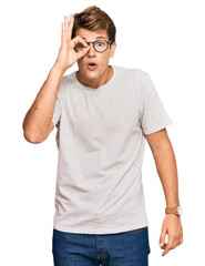 Fototapeta premium Handsome caucasian man wearing casual clothes and glasses doing ok gesture shocked with surprised face, eye looking through fingers. unbelieving expression.