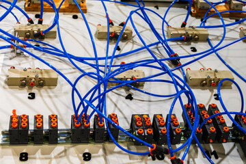 A close-up of a hydraulic training rig with numerous blue hoses and various valves connected to a...