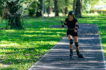 Fototapeta premium Woman rollerblading gracefully in a park, enjoying the fresh air and exercise. The setting showcases vibrant greenery, promoting an active and healthy outdoor lifestyle