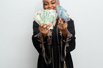 excited and happy african muslim lady holding some money