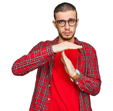 Hispanic young man wearing casual clothes doing time out gesture with hands, frustrated and serious face