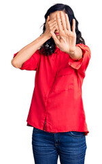 Young beautiful hispanic woman wearing casual clothes covering eyes with hands and doing stop...