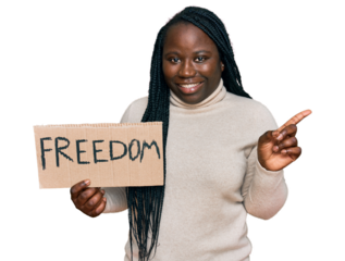 Young black woman with braids holding freedom banner smiling happy pointing with hand and finger to the side