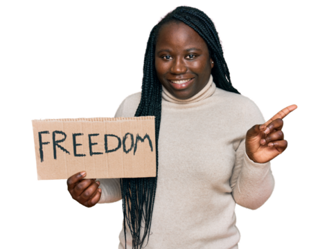 Young black woman with braids holding freedom banner smiling happy pointing with hand and finger to the side