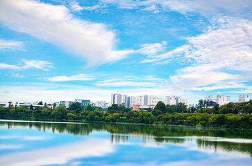 Fototapeta premium Tranquil water of clean pond reflecting skyscrapers and cloudy sky in central park