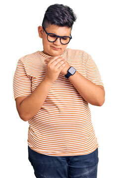 Little boy kid wearing casual clothes and glasses suffering pain on hands and fingers, arthritis inflammation