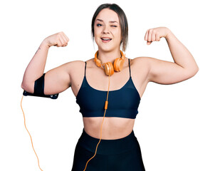 Young hispanic girl wearing sportswear doing strong gesture winking looking at the camera with sexy...