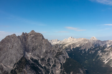 Fototapeta premium Hiking trail with scenic view of rugged mountain peak Jalovec in wild Julian Alps seen from Triglav National Park, Vrsic pass, Slovenia. Wanderlust Slovenian Alps. Sharp steep ridges in alpine terrain