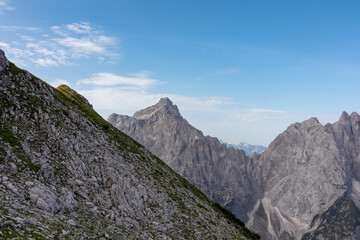 Obraz premium Hiking trail with scenic view of rugged mountain peak Razor in Julian Alps seen from Triglav National Park, Vrsic pass, Slovenia. Wanderlust wild Slovenian Alps. Sharp steep ridges in alpine terrain