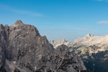 Hiking trail with scenic view of rugged mountain peak Jalovec in wild Julian Alps seen from Triglav...