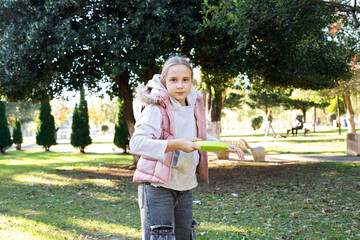 Throwing happy girl child playing flying disc in a sunny, green outdoor setting, exemplifying...