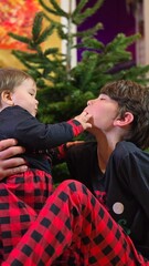 Brother and sister at home in front of the Christmas tree
