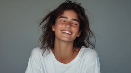 Fototapeta premium Portrait of a cheerful woman with a natural smile, wearing a casual white shirt against a neutral background.