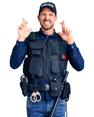 Young handsome man wearing police uniform gesturing finger crossed smiling with hope and eyes closed. luck and superstitious concept.