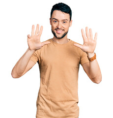 Fototapeta premium Hispanic man with beard wearing casual t shirt showing and pointing up with fingers number nine while smiling confident and happy.