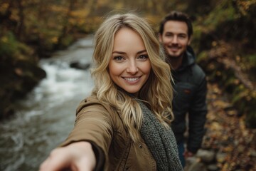 Obraz premium A couple is smiling and posing for a picture by a river