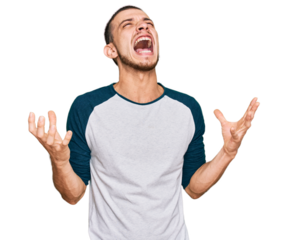 Hispanic young man wearing casual clothes crazy and mad shouting and yelling with aggressive expression and arms raised. frustration concept.