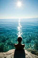 Obraz premium Person sits sunlit rock, clear ocean view.