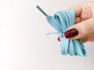 Blue shoe laces in hand on a white background. Space for text.